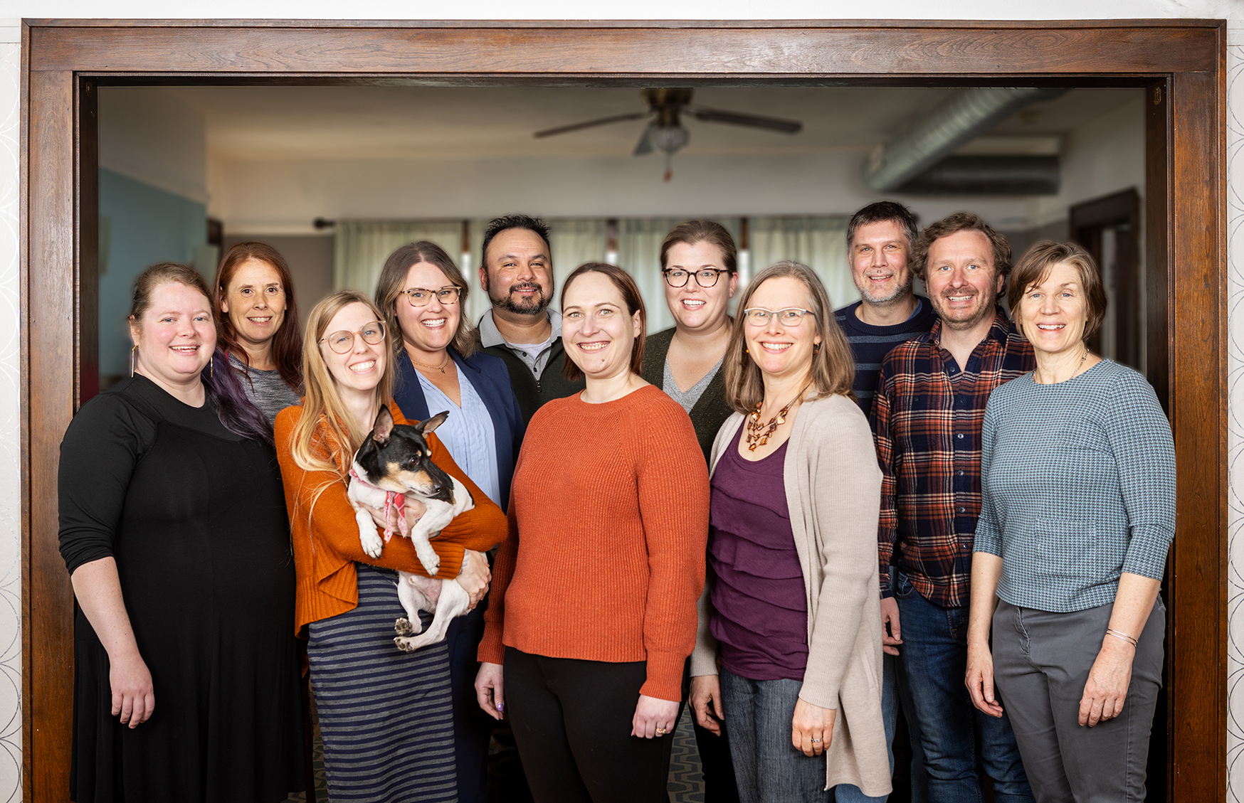 Greenleaf staff members posing standing in a doorway with a small dog